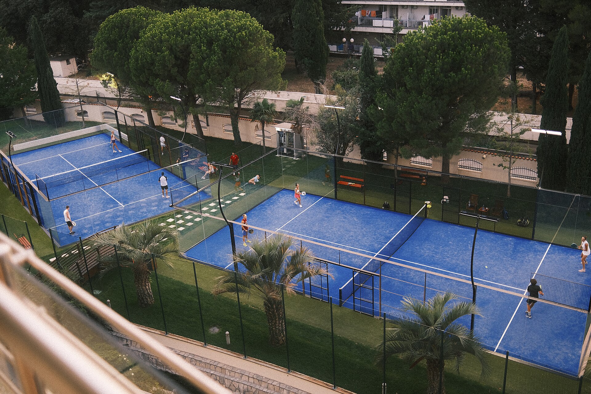 Players enjoying a social padel match on blue outdoor courts