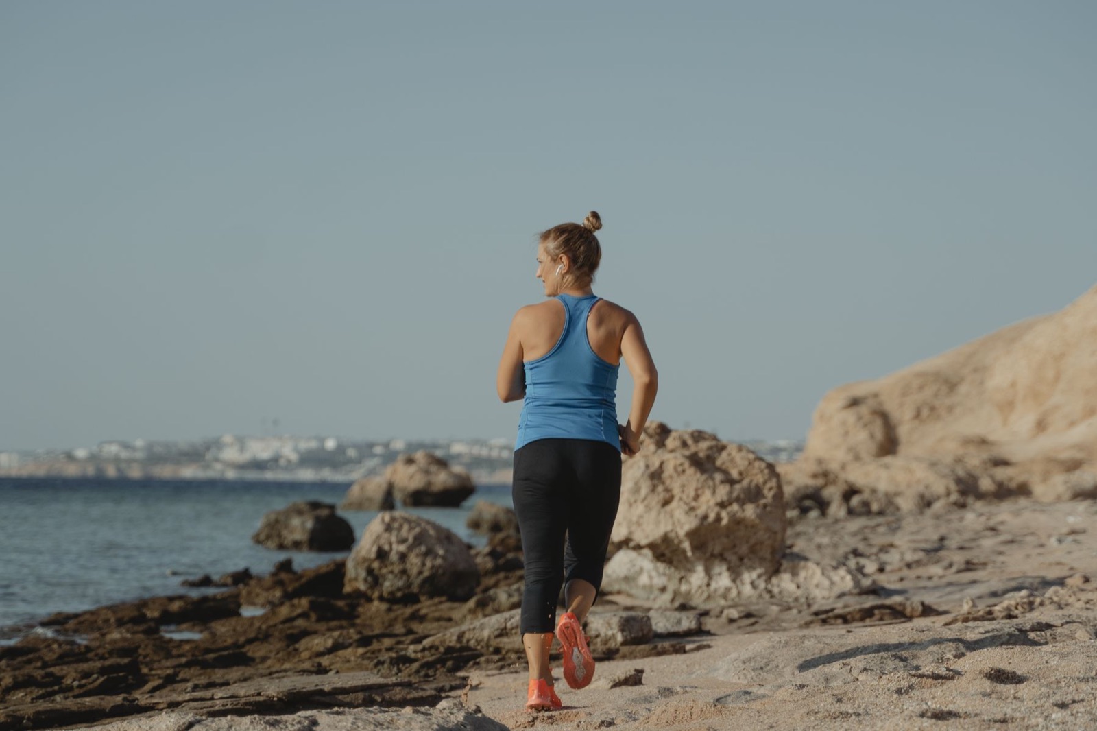 A runner moving along a rocky coastline beside the sea