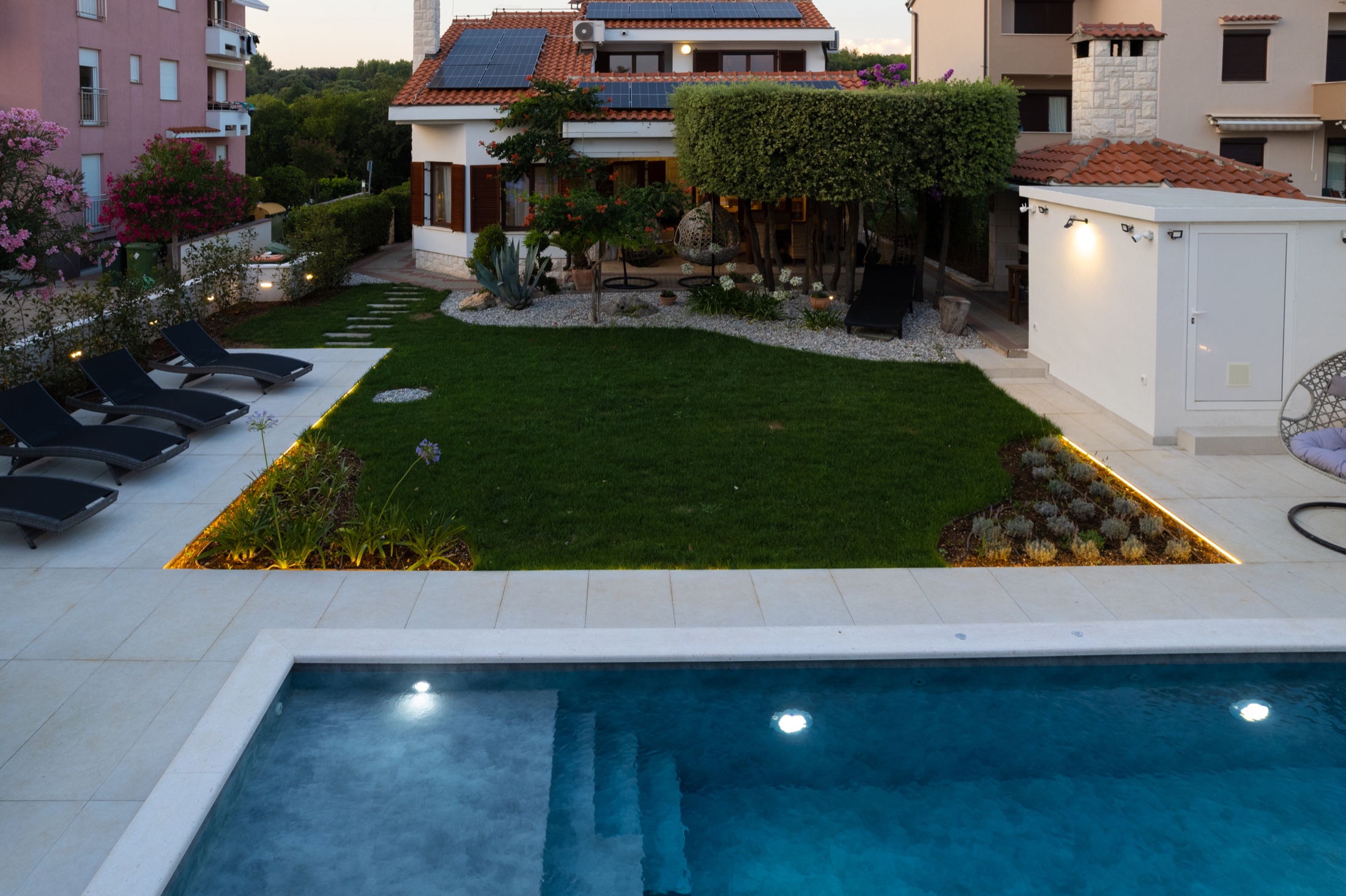 Villa Lostura’s illuminated garden and pool at dusk