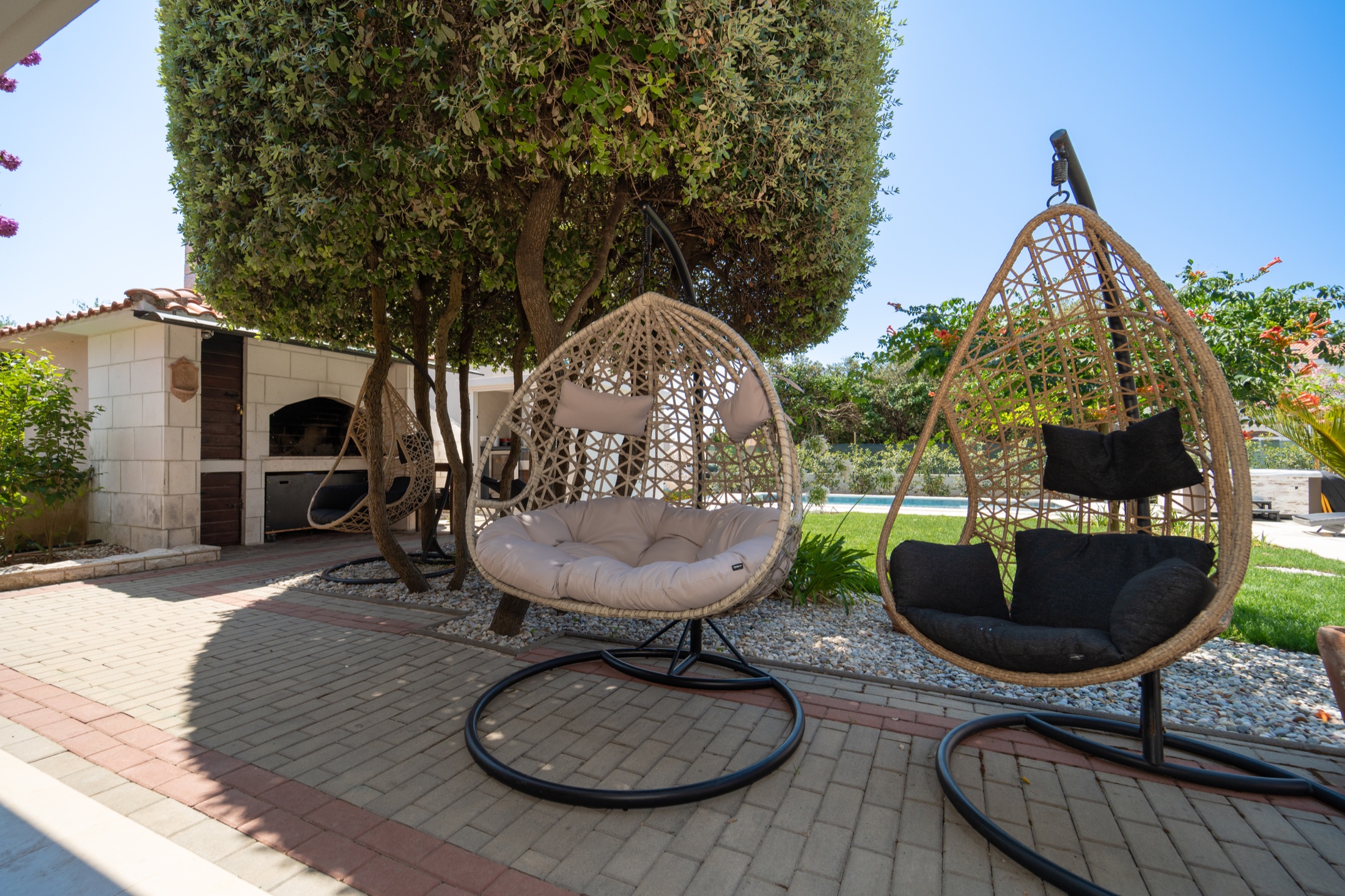 Hanging chairs in a shaded corner of Villa Lostura’s garden