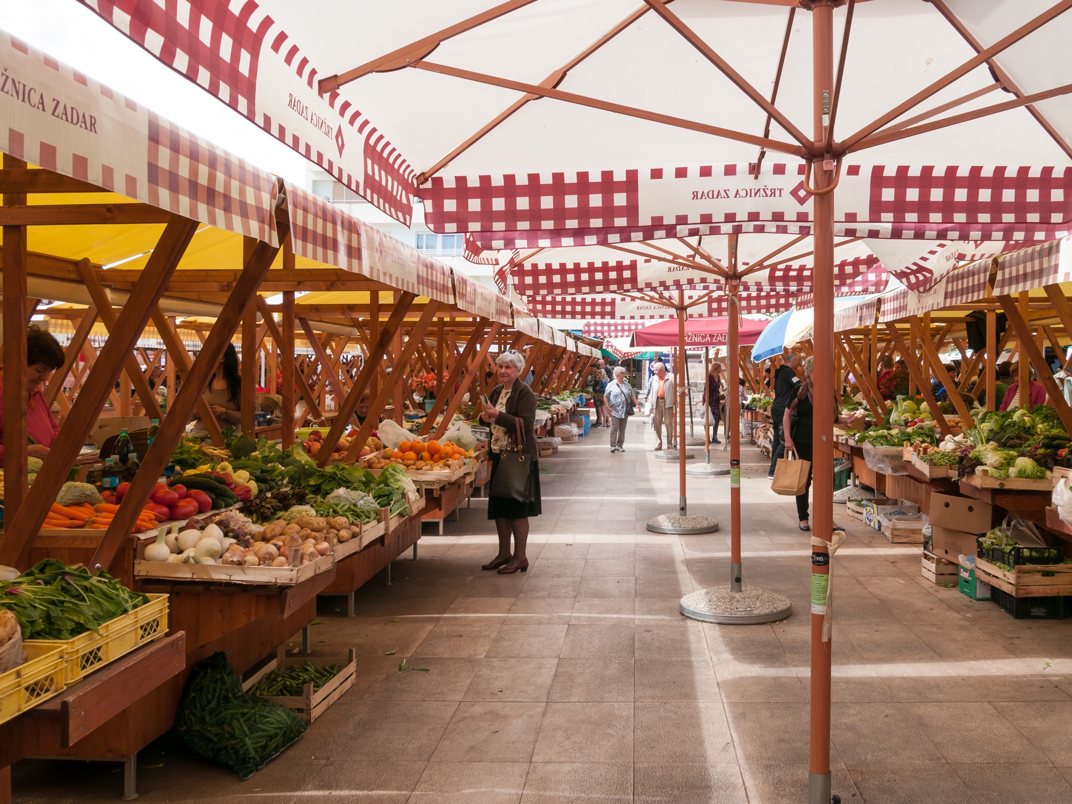 Fresh vegetables and local shoppers beneath the striped canopies of Zadar City Market