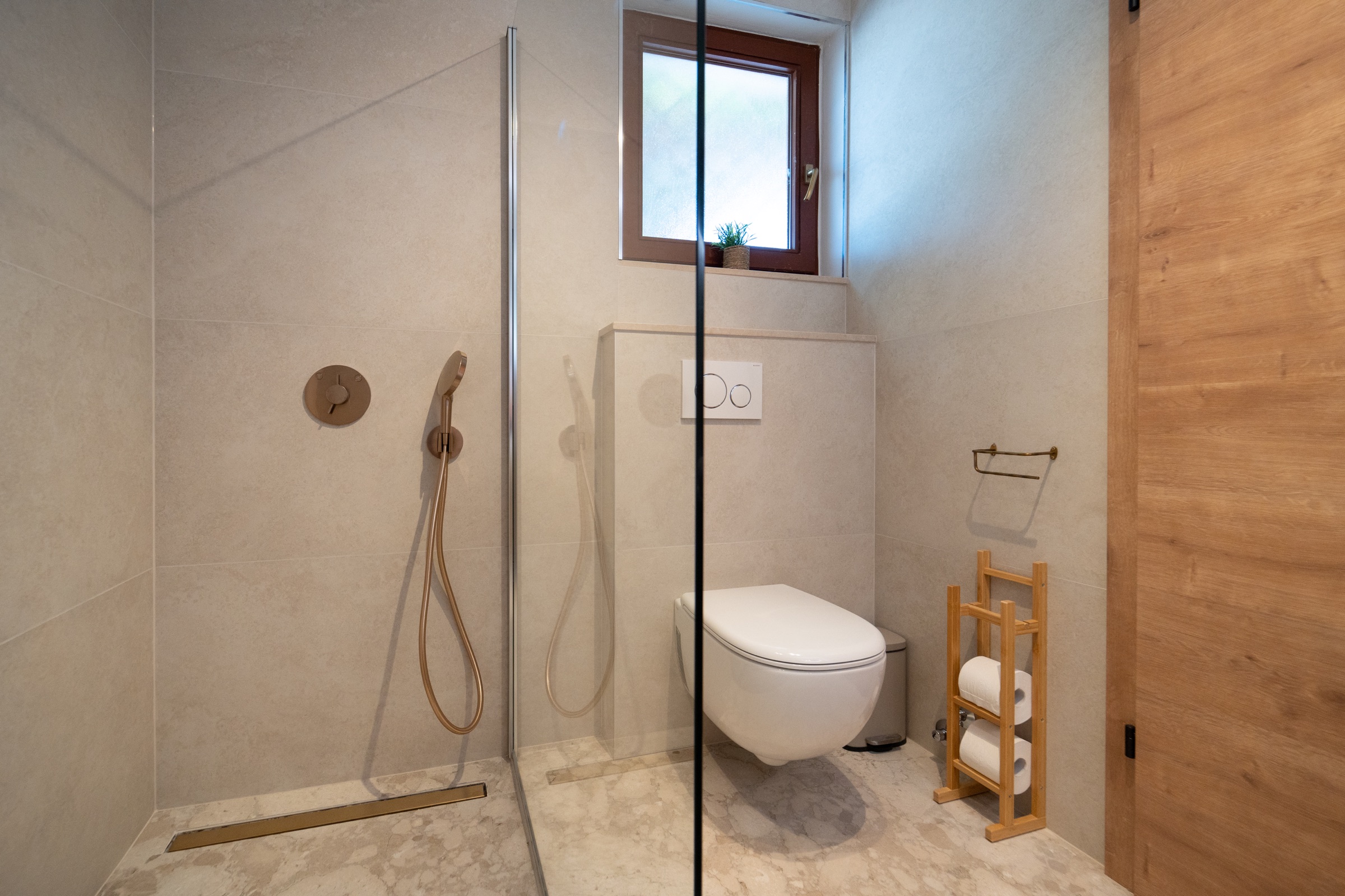 Neutral stone bathroom at Villa Lostura with a walk-in shower and separate toilet area