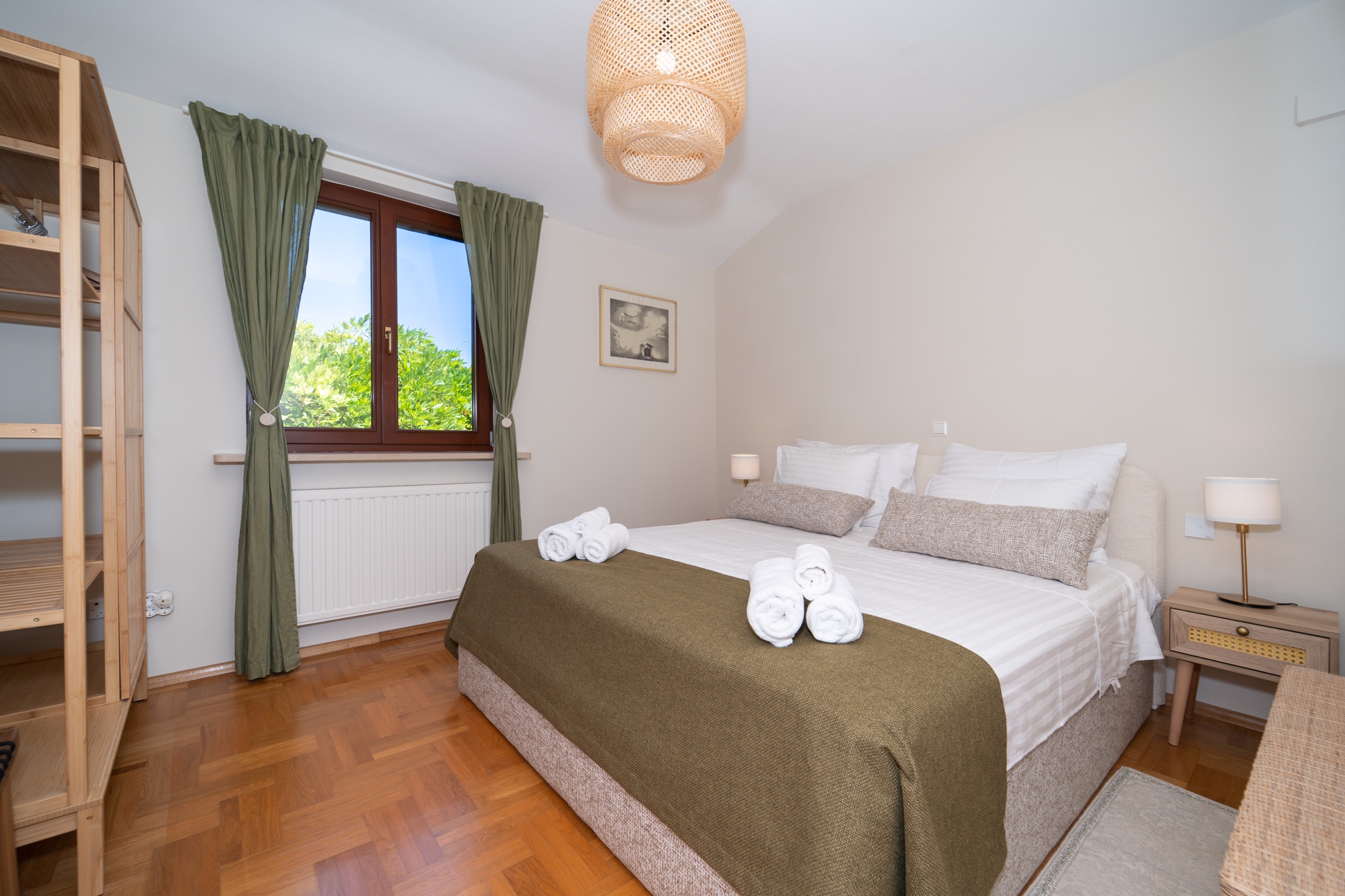 Second and separate green double bedroom with olive textiles and a garden-facing window