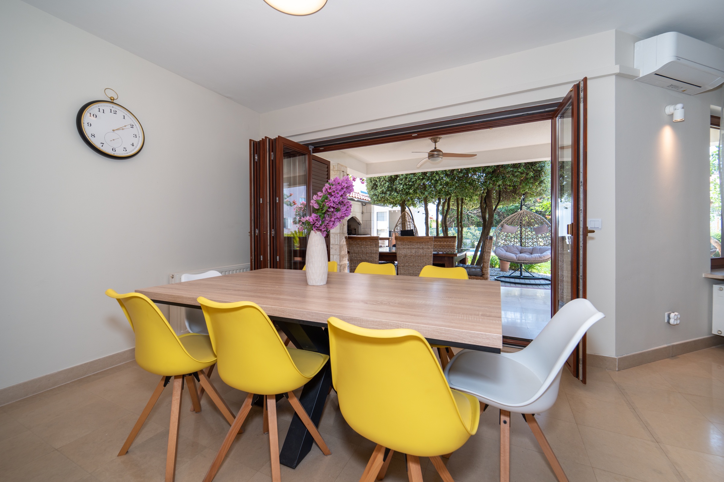 Indoor dining room opening fully onto Villa Lostura’s shaded garden terrace