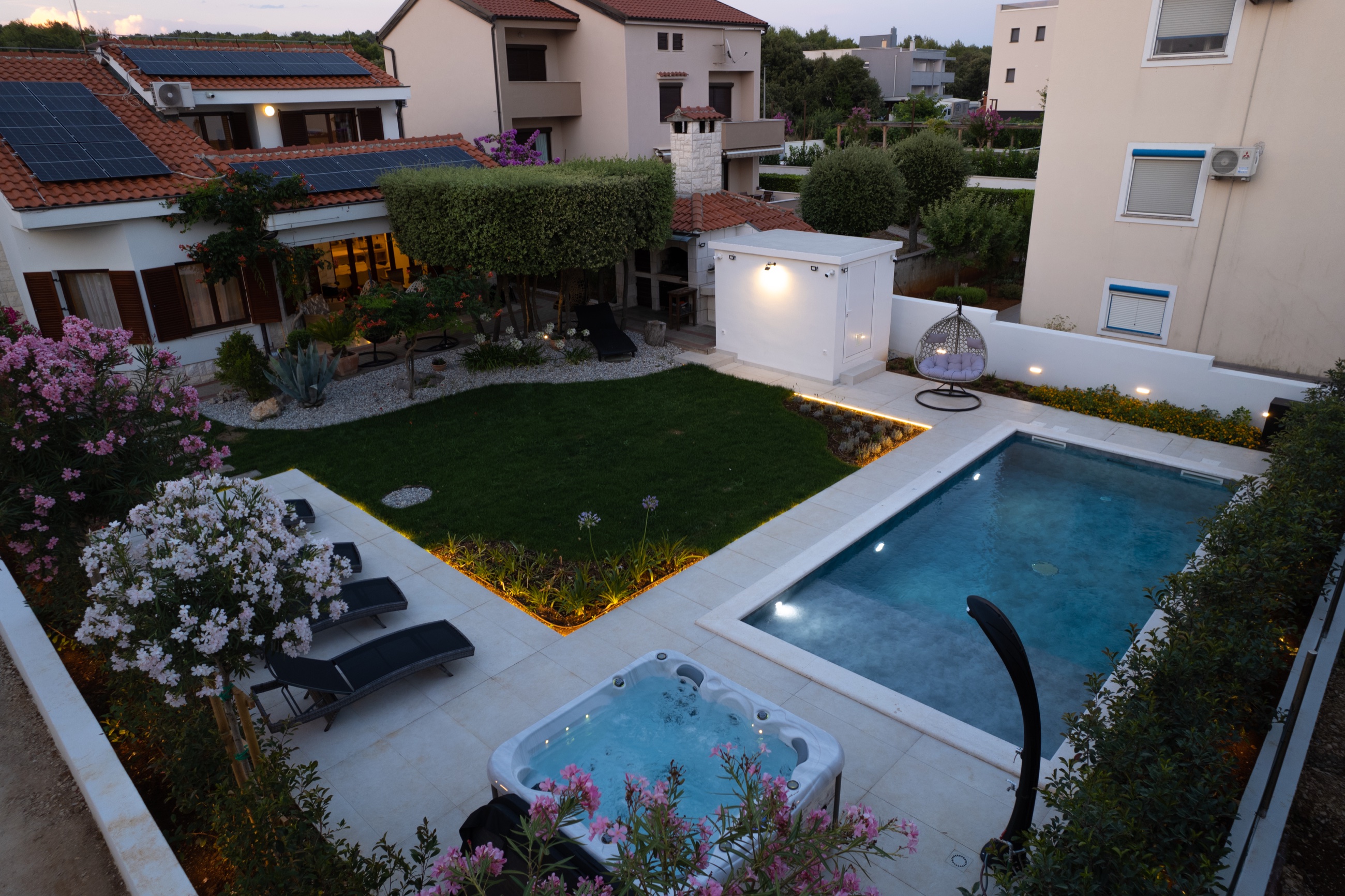 Villa Lostura at dusk, with its illuminated Mediterranean garden, private pool and jacuzzi