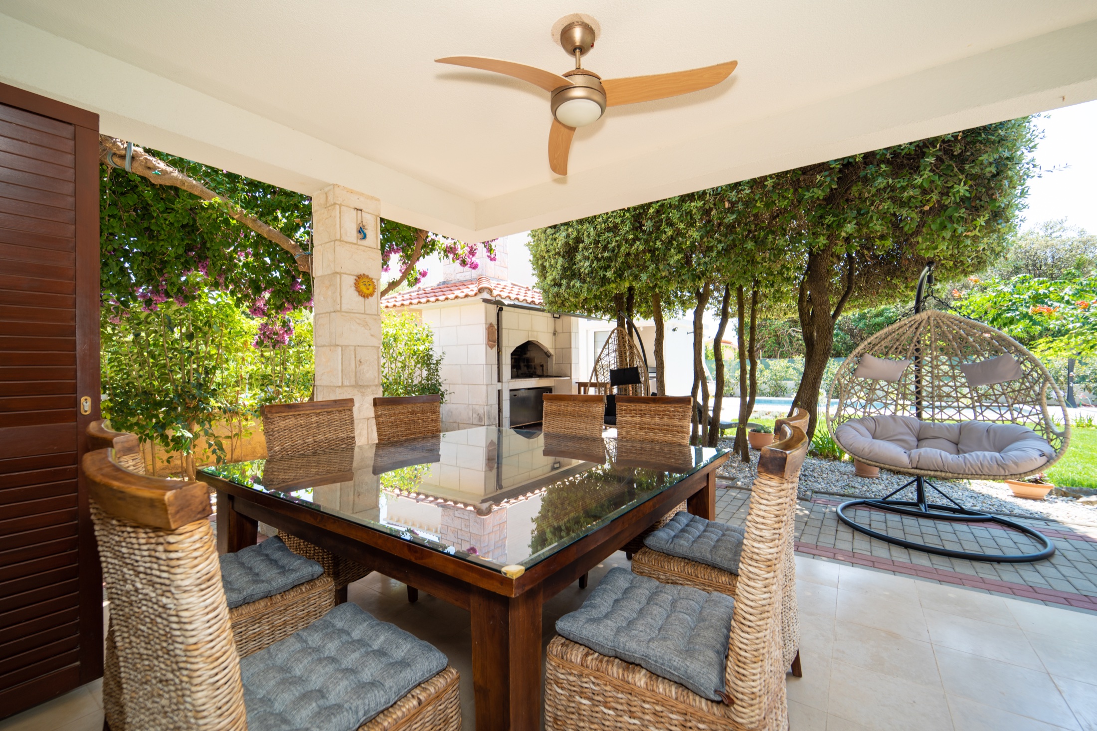 Villa Lostura’s outdoor table and traditional chimney grill beneath the Mediterranean trees